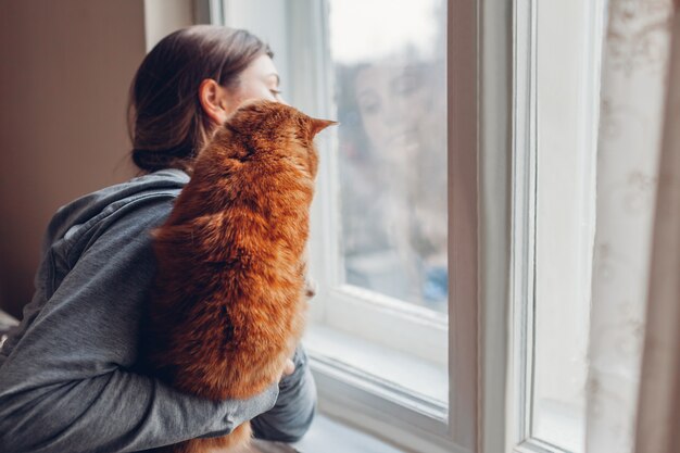 Isolamento a casa durante la pandemia di coronavirus covid-19. Donna che esamina finestra con il gatto. Stai al sicuro bloccato in quarantena