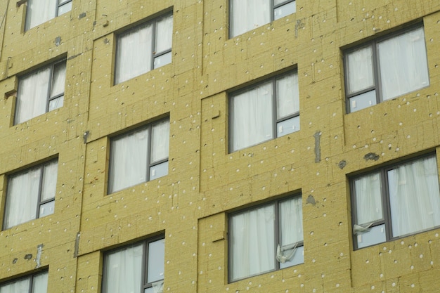 Isolamento termico durante la costruzione di un condominio. Installazione di protezione dal calore industriale in un cantiere edile.