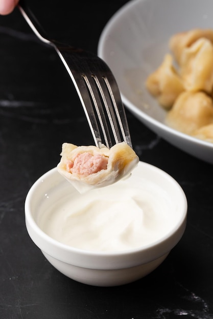 Isolato tradizionale russo pelmeni ravioli gnocchi con immersione di carne in panna acida su sfondo nero Menu o libro di cucina concept