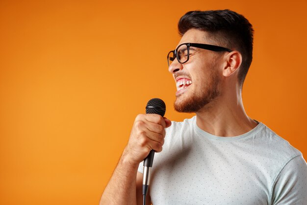 Ispanico giovane uomo bello che canta con gioia nel microfono clsoe