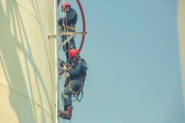 Ispezione di sicurezza dell'altezza di accesso della fune del lavoratore di sesso maschile dell'olio di accumulo di spessore