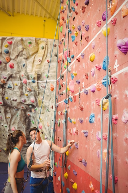 Istruttore che mostra la parete di arrampicata della donna