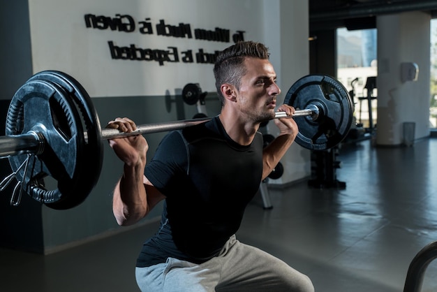 Istruttore di fitness che fa squat con bilancieri