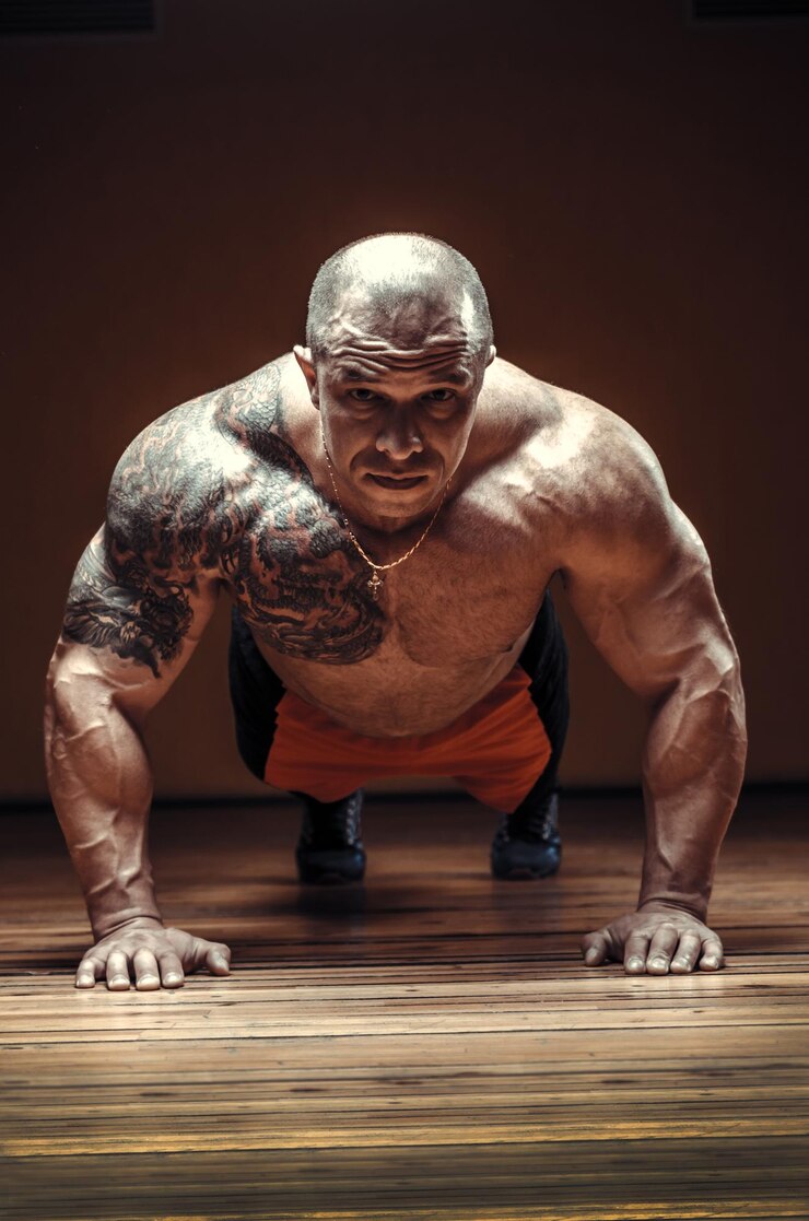 Istruttore di fitness crossfit professionale con tatuaggio Lo sportivo maschio sta facendo flessioni allenandosi al chiuso