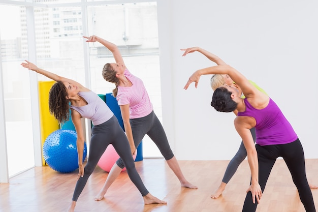 Istruttore e amici femminili che fanno esercizio di stretching