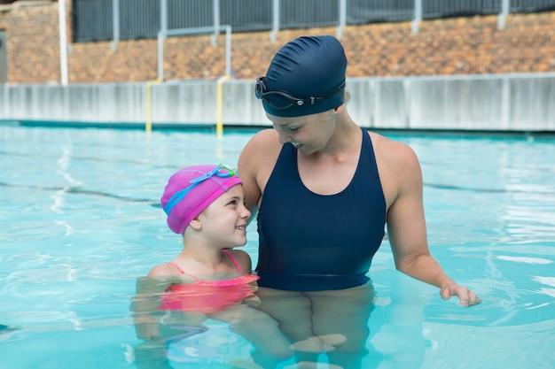 Istruttore femminile e ragazza che si distendono in piscina