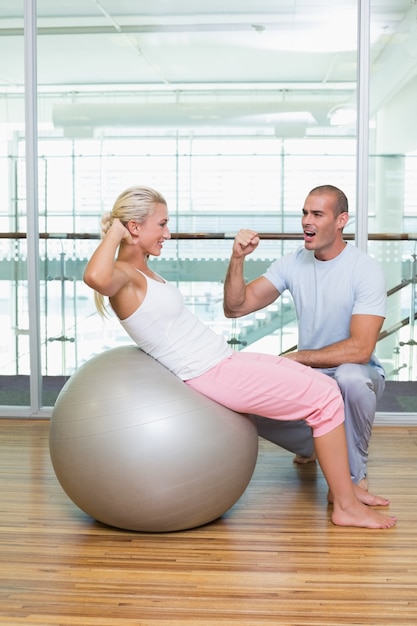 Istruttore maschio che assiste donna con gli scricchiolii addominali alla palestra