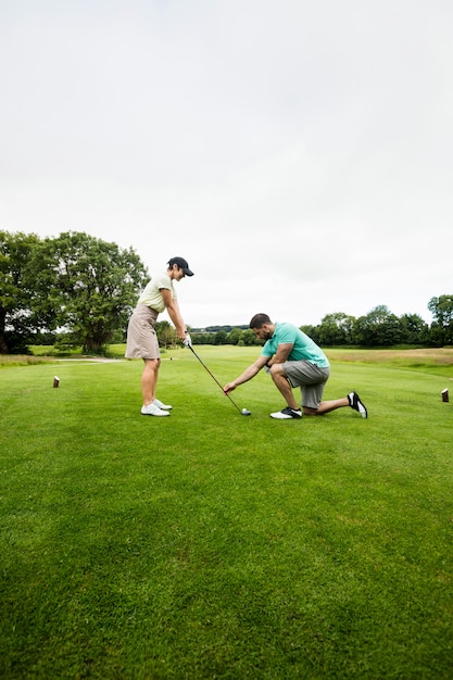 Istruttore maschio che assiste donna nell'apprendimento del golf