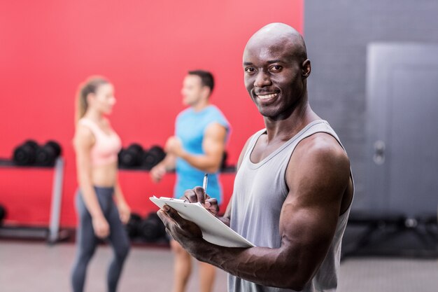 Istruttore muscolare sorridente che scrive sulla lavagna per appunti