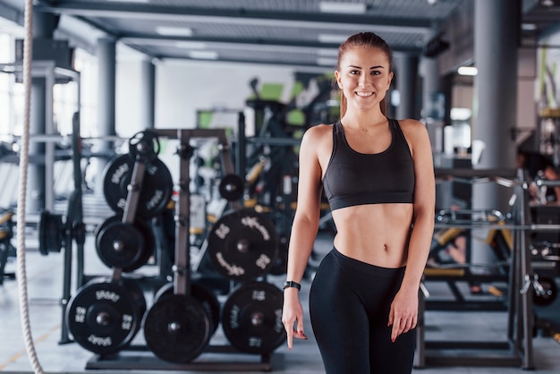 Istruttore personale di fitness femminile giovane con blocco note in piedi in palestra.