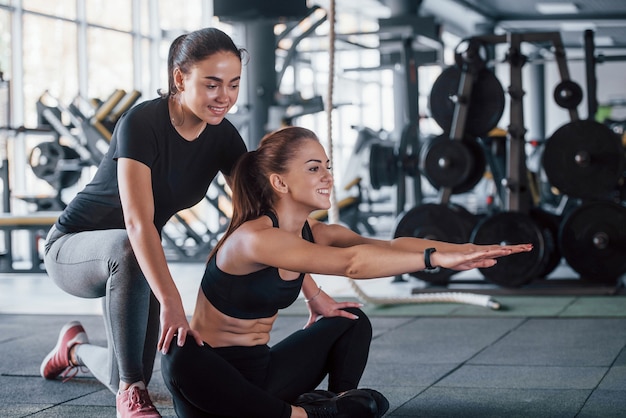 Istruttore personale femminile che aiuta la donna a fare esercizi in palestra.