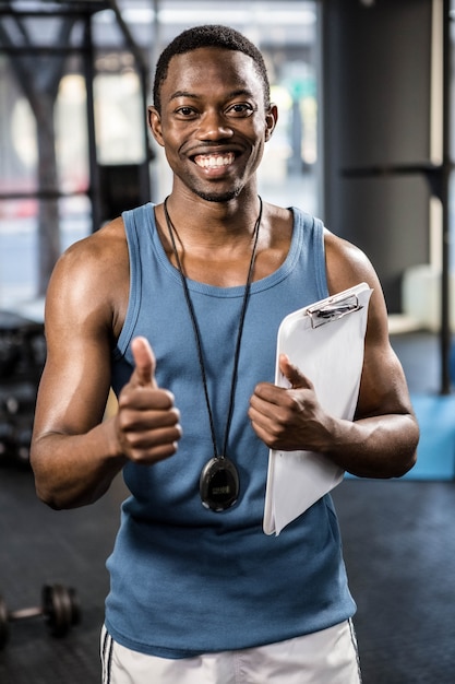 Istruttore sorridente che mostra i pollici su alla palestra del crossfit