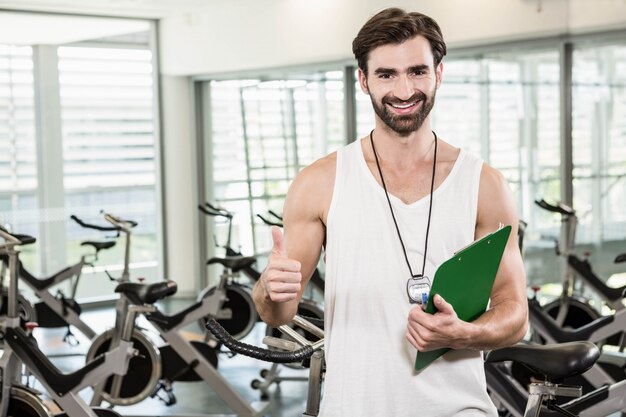 Istruttore sorridente che mostra pollice in su in palestra