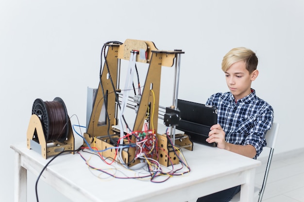 Istruzione, bambini, concetto di tecnologia. il ragazzo adolescente sta stampando sulla stampante 3d.