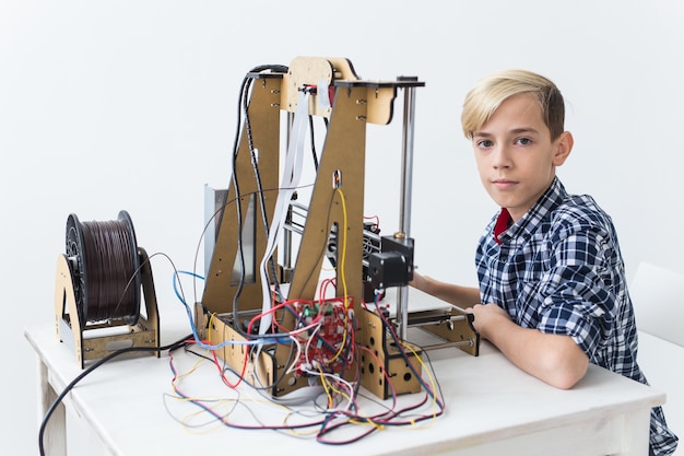 Istruzione, bambini, concetto di tecnologia - il ragazzo teenager sta stampando sulla stampante 3d.