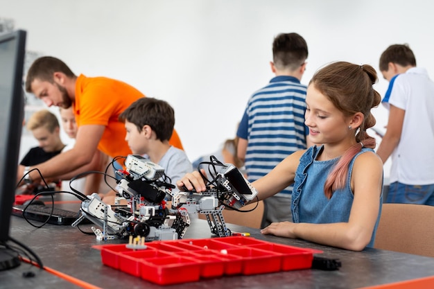 Istruzione, bambini, tecnologia, scienza e concetto di persone - gruppo di bambini felici con computer portatili che costruiscono robot alla lezione di robotica