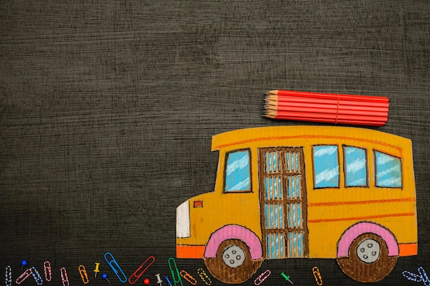 Istruzione e concetto di ritorno a scuola Vista dall'alto dello scuolabus in cartone e della cancelleria delle matite con sfondo lavagna