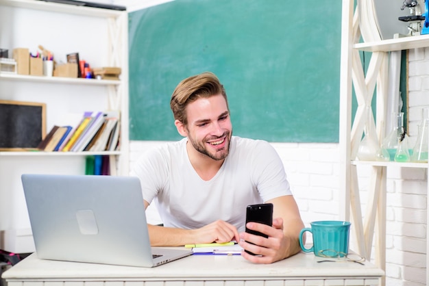 Istruzione moderna torna a scuola Giornata lavorativa mattina vita universitaria insegnante di scuola uso computer e telefono uomo prendere appunti e bere caffè studente uomo in classe con tazza di tè gioco per computer