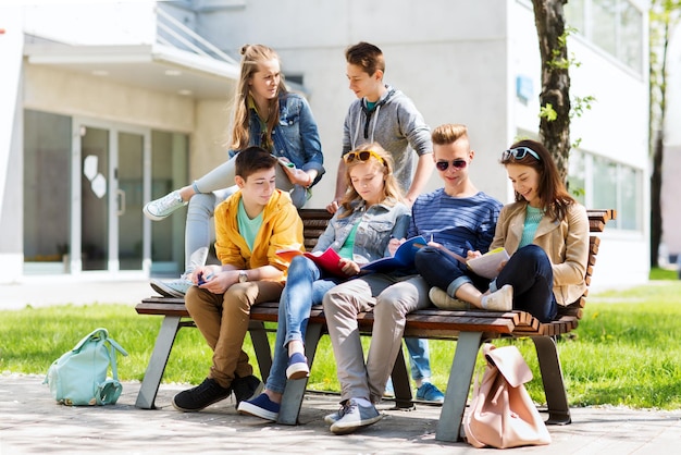 istruzione, scuola superiore e concetto di persone - gruppo di studenti adolescenti felici con quaderni che imparano nel cortile del campus