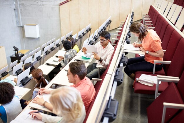 istruzione, scuola superiore, università, apprendimento e concetto di persone - gruppo di studenti internazionali che scrivono test in aula