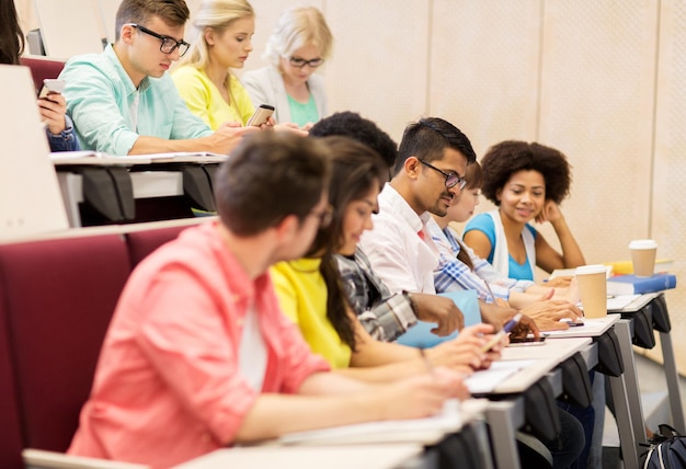 istruzione, scuola superiore, università, apprendimento e concetto di persone - gruppo di studenti internazionali con quaderni e test di scrittura del caffè in aula