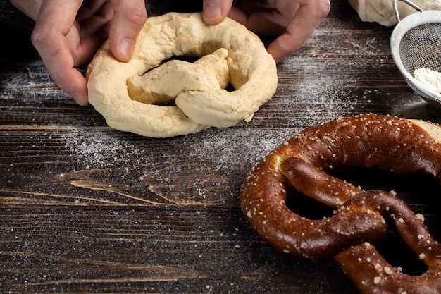 Istruzioni dettagliate per preparare i pretzel. Il cuoco stende la pasta e stende il pretzel