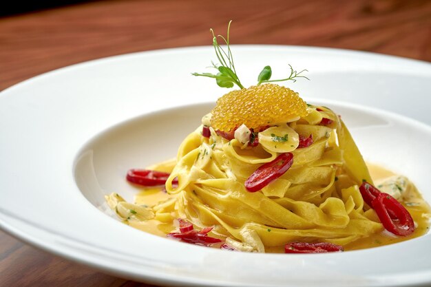 Italian Pepperoncini Pasta con aglio, peperoncino e caviale di luccio in un piatto bianco su fondo di legno