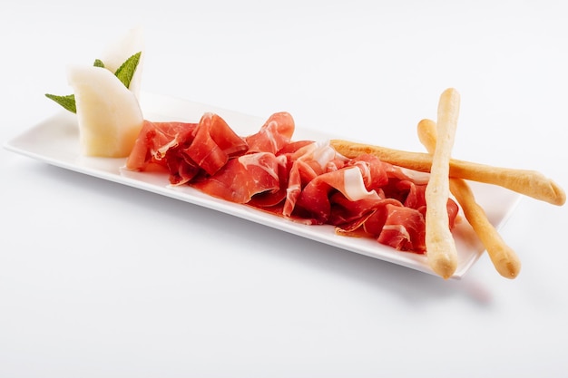 Jamon Serrano Prosciutto Crudo o prosciutto di Parma e grissini su piatto bianco