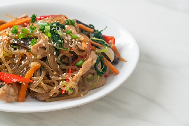 Japchae o vermicelli coreani saltati in padella con verdure e maiale conditi con sesamo bianco Stile alimentare tradizionale coreano