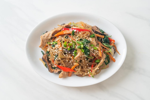 japchae o vermicelli coreani saltati in padella con verdure e maiale conditi con sesamo bianco - stile alimentare tradizionale coreano