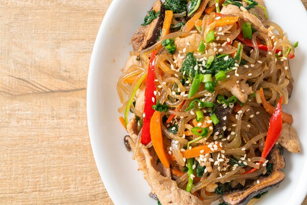 japchae o vermicelli coreani saltati in padella con verdure e maiale conditi con sesamo bianco - stile alimentare tradizionale coreano