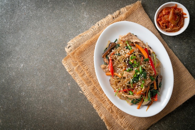 Japchae o vermicelli coreani saltati in padella con verdure e maiale conditi con sesamo bianco