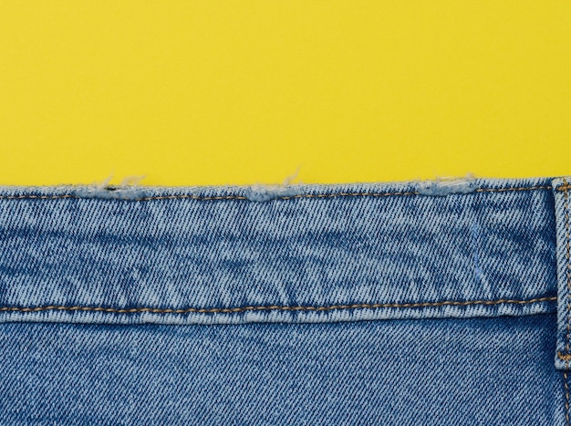 Jeans blu su uno spazio di copia sullo sfondo giallo
