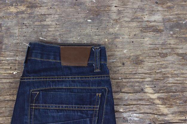 Jeans blu sulla vecchia tavola di legno. Spazio per il testo.