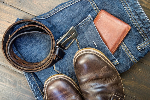 Jeans cintura scarpe e portafoglio su sfondo di legno