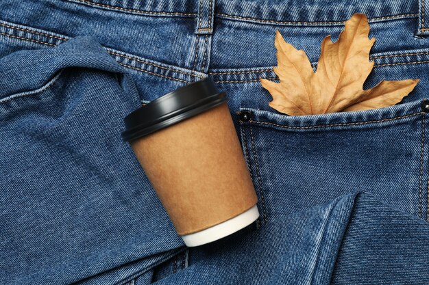 Jeans con foglia in tasca e bicchiere di carta, spazio per il testo