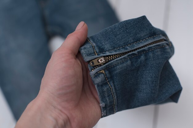 Jeans con una cerniera in una mano femminile.