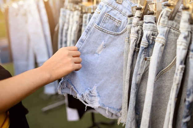 Jeans d'acquisto della persona nel mercato delle pulci