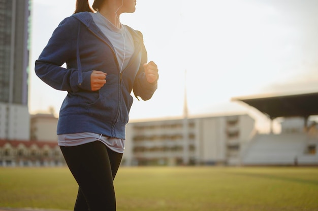 Jogging, fitness, corsa, esercizio fisico, stile di vita, concetto sano. Le giovani donne riscaldano il corpo. Siediti e bevi il resto delle proteine del siero di latte dopo aver fatto jogging sulla pista da corsa intorno al campo di calcio.