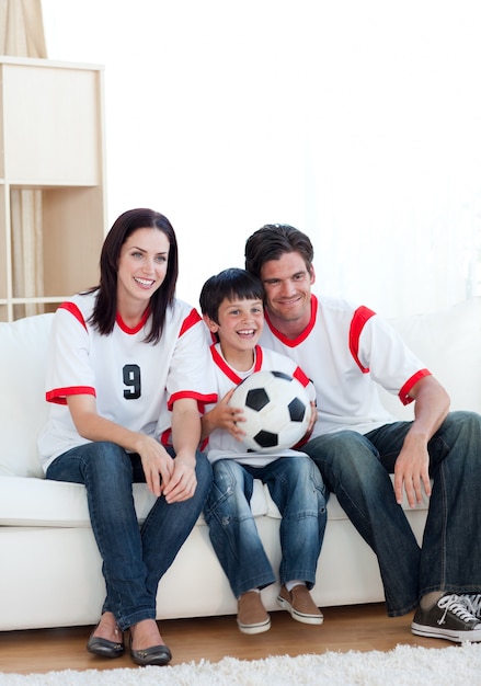 Jolly giovane famiglia a guardare una partita di calcio