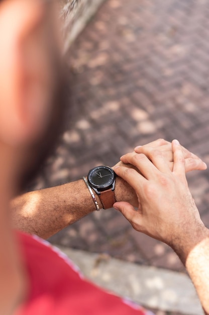 Joven mirando su reloj de muñeca en el parque, toma cerrada