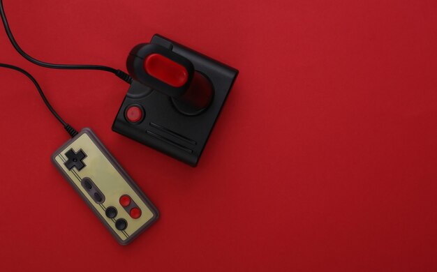 Joystick retrò e gamepad su sfondo rosso. Gioco, competizione di videogiochi. Vista dall'alto