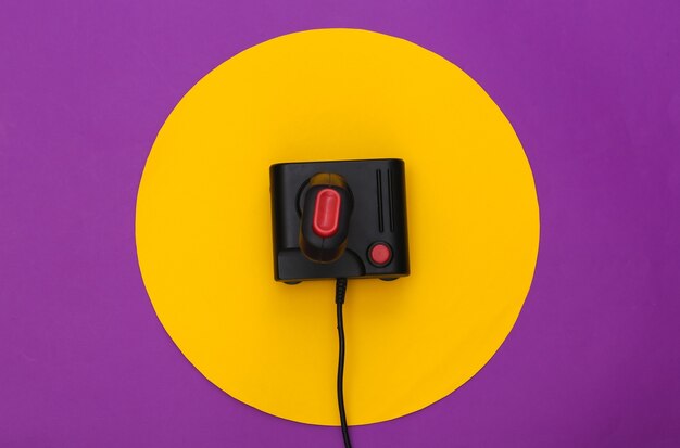 Joystick retrò su sfondo viola con cerchio giallo. Colpo concettuale dello studio. Minimalismo. Vista dall'alto
