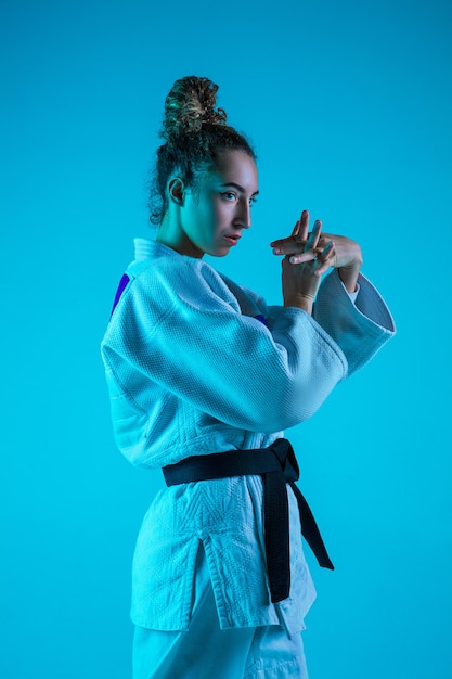 Judoist femminile professionista in posa isolato su sfondo blu studio in neon