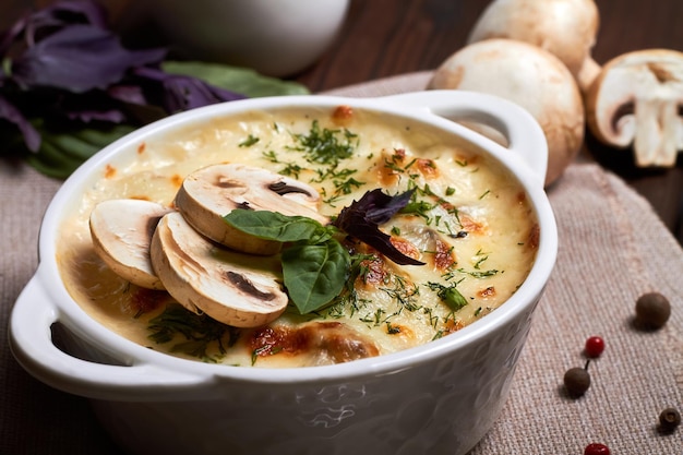 Julienne di pollo con funghi e erbe aromatiche in piatto bianco su tavola di legno