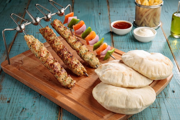 Kabab di pollo con salsa di pane e patatine fritte isolate sulla vista laterale del tagliere sul fastfood della tavola