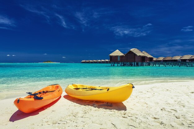 Kayak gialli e arancioni sulla spiaggia tropicale con ville