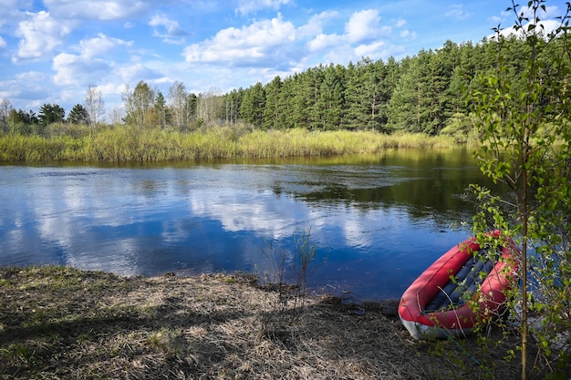 Kayak gonfiabile rosso vicino alla riva del fiume forestale