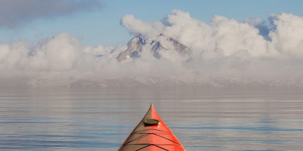 Kayak in mare nell'acqua del ghiacciaio vicino alle cime delle montagne rocciose