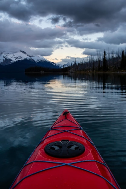 Kayak in un tranquillo e calmo lago glaciale durante un vibrante tramonto nuvoloso